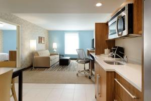 Home2 Suites by Hilton Milwaukee Airport في ميلووكي: غرفه فندقيه مع مطبخ وصاله