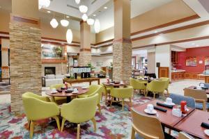 Hilton Garden Inn Milwaukee Airport في ميلووكي: تقديم مطعم بالطاولات والكراسي