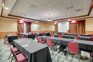 Hilton Garden Inn Milwaukee Airport في ميلووكي: قاعة اجتماعات مع طاولات وكراسي حمراء