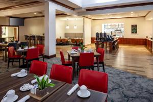 a restaurant with wooden tables and red chairs at Hilton Garden Inn Chicago O'Hare Airport in Des Plaines