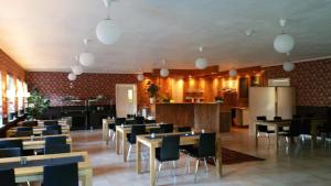 a dining room with tables and chairs and a kitchen at Hotel Dalhem in Dalhem