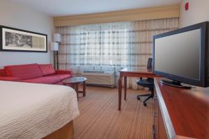 Habitación de hotel con TV de pantalla plana y cama en Courtyard by Marriott Junction City, en Junction City