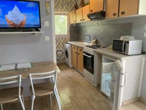 a kitchen with a table and a tv on the wall at F1 noir/anis, avec terrasse couverte et jardin (E) in Compreignac