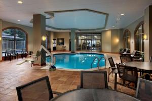 a pool in a hotel lobby with tables and chairs at Embassy Suites by Hilton Austin Arboretum in Austin
