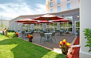 a patio with tables and chairs with red umbrellas at Hilton Garden Inn Cincinnati Blue Ash in Blue Ash