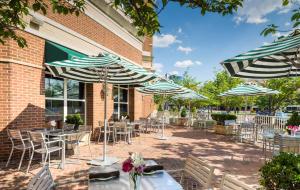 a patio with tables and chairs and umbrellas at Hilton Alexandria Old Town in Alexandria