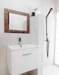 uma casa de banho branca com um lavatório e um espelho em La place em Mactan