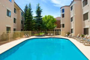 una piscina en un patio con sillas y un edificio en Embassy Suites by Hilton Flagstaff, en Flagstaff