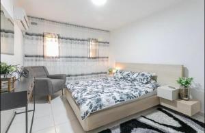 a bedroom with a large bed and a chair at Kamer guesthouse in Beer Sheva