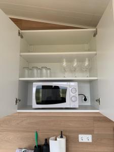 a white microwave in a kitchen with glasses on shelves at Skammidalur cottages in Vík