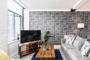 a living room with a couch and a tv at Newly Refurbished Stylish Central Apartment in Bradford