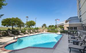 einen Pool mit Gartenmöbeln und ein Gebäude in der Unterkunft Hampton Inn & Suites N Ft Worth-Alliance Airport in Roanoke