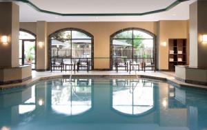 a swimming pool with tables and chairs in a building at Embassy Suites by Hilton Houston Near the Galleria in Houston