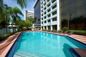 棕榈滩花园Embassy Suites by Hilton Palm Beach Gardens PGA Boulevard的带椅子的游泳池和一栋建筑