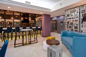 a lobby with a blue couch and a table and chairs at Hampton Inn NY-JFK in Queens