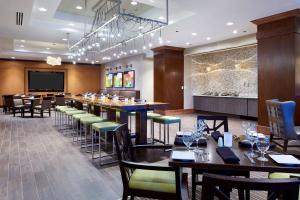 a restaurant with a long bar with tables and chairs at Hilton Minneapolis-St Paul Airport in Bloomington