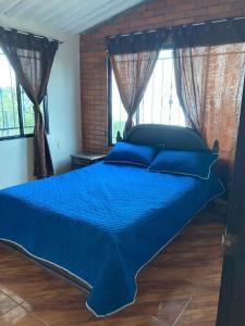 un grande letto blu in una camera da letto con finestre di Casa Montañita del RIO a Aratoca