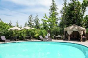 una piscina con sillas, mesas y sombrillas en Hilton Santa Cruz Scotts Valley, en Santa Cruz