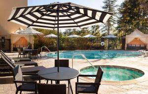 a pool with tables and chairs and an umbrella at Hilton Santa Cruz Scotts Valley in Santa Cruz