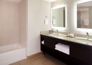 a bathroom with two sinks and a tub and a mirror at Hilton Santa Cruz Scotts Valley in Santa Cruz