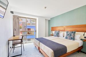 a bedroom with a bed and a desk and a window at Hotel Torre Del Conde in San Sebastián de la Gomera