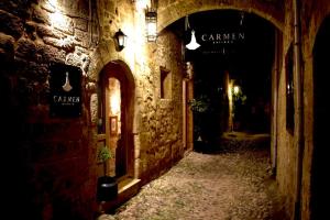a dark alley with a stone building with signs on it at Carmen Art Hotel in Rhodes Town