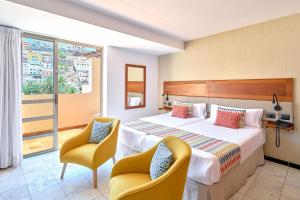 サン・セバスティアン・デ・ラ・ゴメラにあるHotel Torre Del Condeのベッド1台と椅子2脚が備わるホテルルームです。