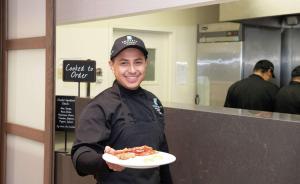 a man holding a plate of food in a kitchen at Embassy Suites by Hilton Walnut Creek in Walnut Creek
