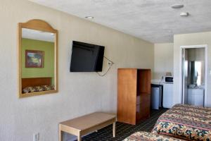a hotel room with a bed and a flat screen tv at Executive Inn of Arlington, Near AT&T Stadium in Arlington