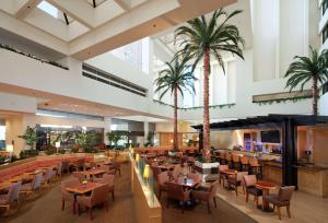 un ristorante con palme, tavoli e sedie di Hilton Orange County/Costa Mesa a Costa Mesa