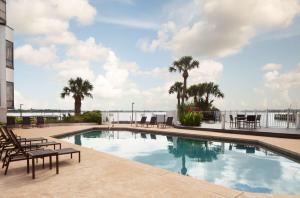 a swimming pool with chairs and a view of the water at Hilton Houston NASA Clear Lake in Seabrook
