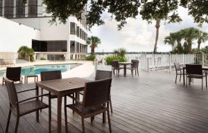 una terraza con mesas y sillas junto a una piscina en Hilton Houston NASA Clear Lake en Seabrook