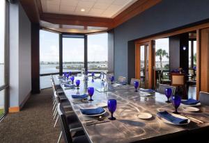 a long table in a restaurant with blue glasses on it at Hilton Houston NASA Clear Lake in Seabrook