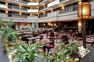 a restaurant with tables and chairs and plants at Embassy Suites by Hilton Dulles Airport in Herndon