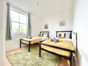 two beds in a room with a window and a rug at Town Centre Flat- Great for Contractors - Sleeps 4 - FREE Parking in Southampton