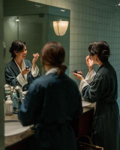 Una donna che si lava i denti davanti allo specchio del bagno di Post Hotel & Spa a Lake Louise
