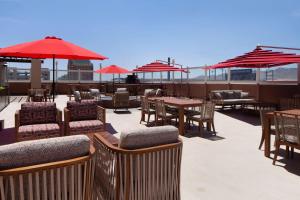 un patio con mesas, sillas y sombrillas rojas en DoubleTree by Hilton El Paso Downtown, en El Paso