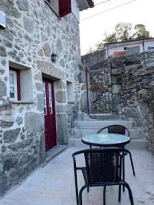 a table and chairs in front of a stone building at Casa dos Pintos in Paredes de Coura