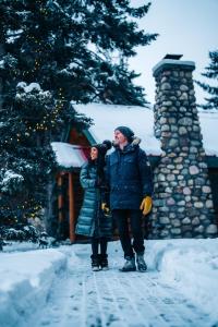 un hombre y una mujer parados en la nieve frente a una cabaña en Post Hotel & Spa, en Lago Louise