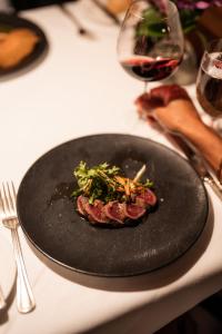 een steak op een zwart bord op een tafel met een glas wijn bij Post Hotel & Spa in Lake Louise