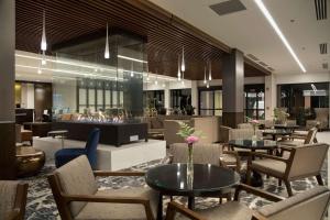 a lobby with tables and chairs and a fireplace at DoubleTree by Hilton Hotel Syracuse in East Syracuse