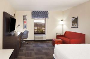 a hotel room with a bed and a chair and a television at Hampton Inn Charleston-Southridge in Charleston