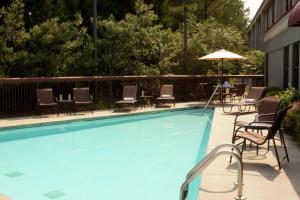 uma piscina com cadeiras, uma mesa e um guarda-sol em Hampton Inn Lawrenceville em Lawrenceville