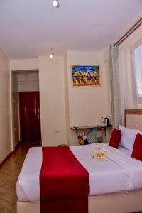 um quarto de hotel com uma cama grande e um cobertor vermelho em Walabi Mara Hotel em Narok