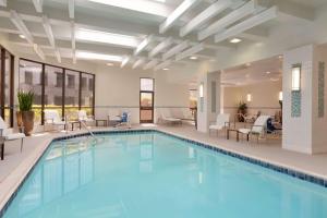 uma piscina num hotel com cadeiras e mesas em Embassy Suites by Hilton Irvine Orange County Airport em Irvine
