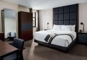 a hotel room with a large bed and a desk at Joinery Hotel Pittsburgh, Curio Collection by Hilton in Pittsburgh