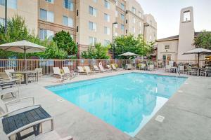 uma piscina com cadeiras, mesas e guarda-sóis em Homewood Suites by Hilton Albuquerque Uptown em Albuquerque