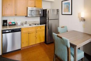 cocina con mesa y nevera de acero inoxidable en Homewood Suites by Hilton Albuquerque Uptown en Albuquerque