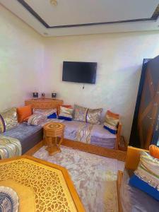 traditional moderne apartment in mohammedia في Ben Yakhlef: غرفة معيشة مع كنبتين وتلفزيون بشاشة مسطحة