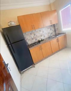 eine Küche mit einem schwarzen Kühlschrank und Holzschränken in der Unterkunft traditional moderne apartment in mohammedia in Ben Yakhlef